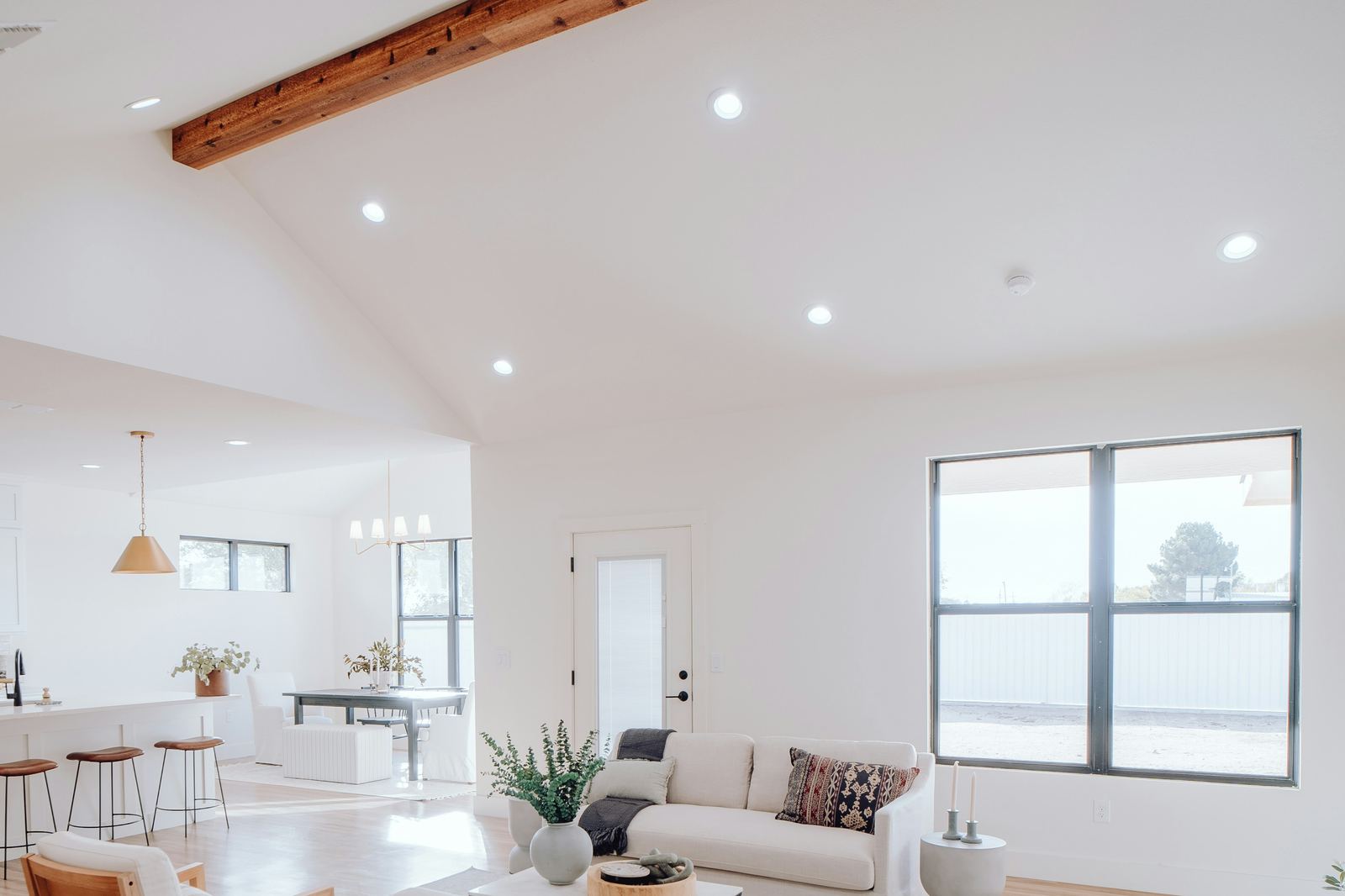Open great room with vaulted ceiling, exposed beam and warm oak floors